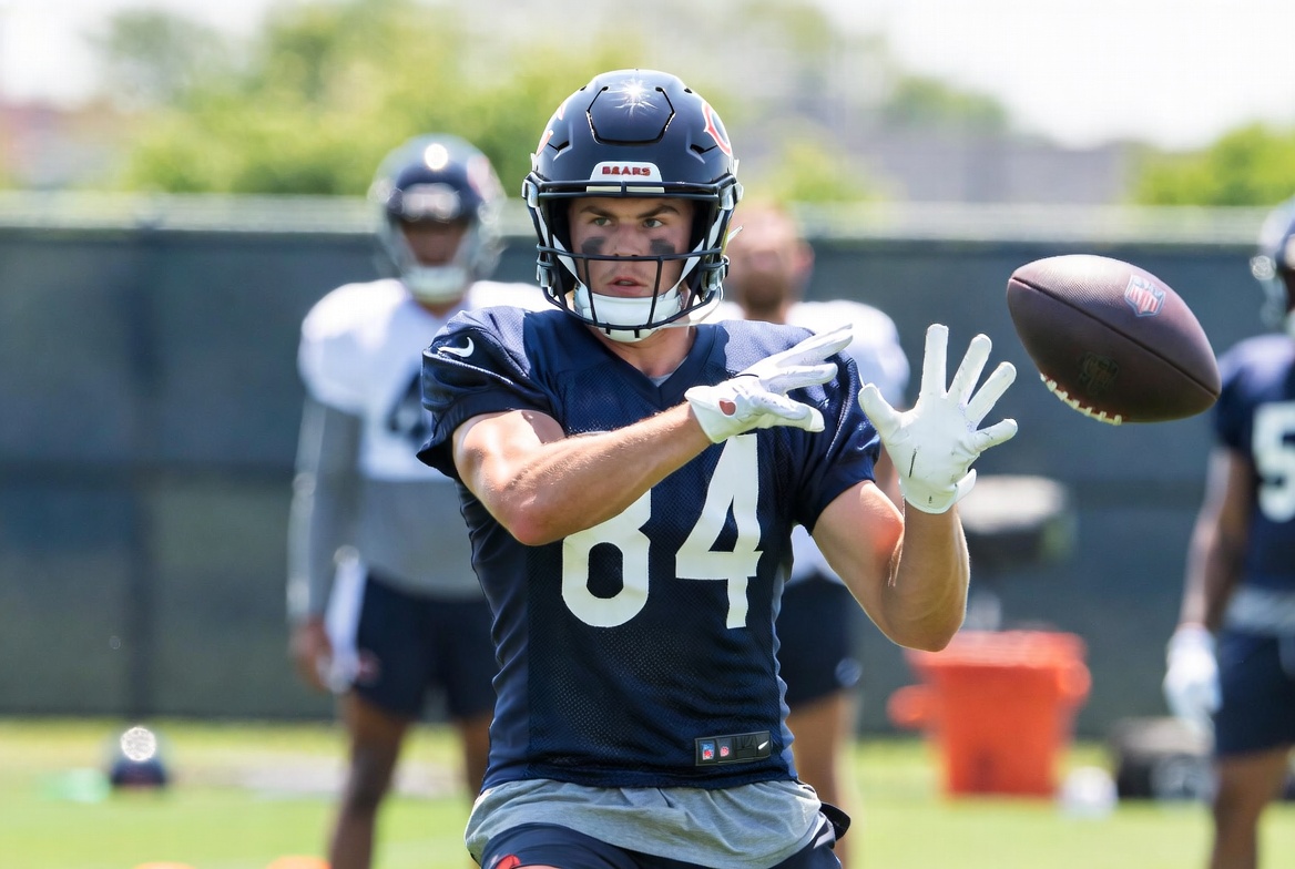 June 2026 minicamp — beat writers and camera crews lined up at the sideline as receivers and DBs run reps.